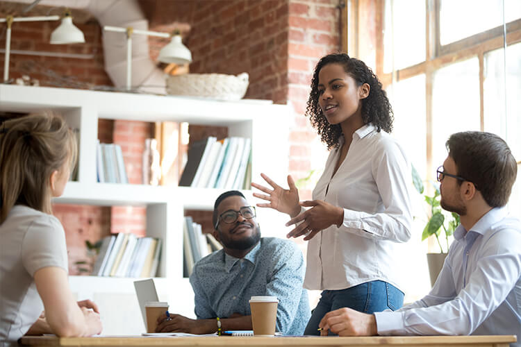 woman standing up and speaking to small group in conference room