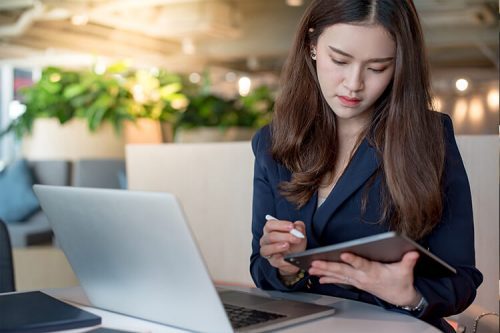 woman works on tablet and laptop