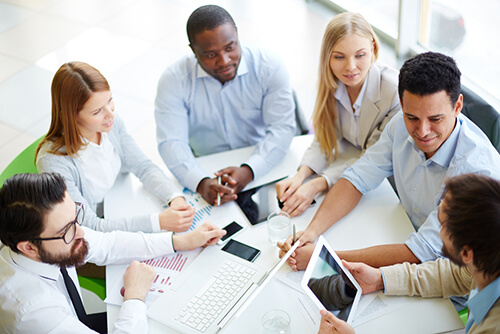 Young professionals sit around a table, talking.