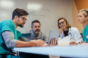 A group of medical professionals gathered around a tablet device