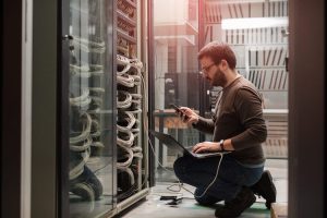 An IT professional working in a server room configures an information system. 