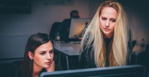 2 digital marketers work on a computer in an office space