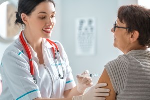 A public health nurse gives a shot to a patient.