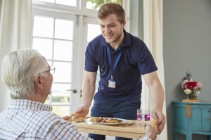 A nursing home staff member assists a resident.