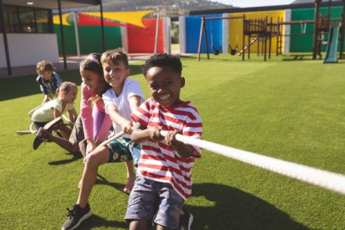 A group of children playing tug of war in the park