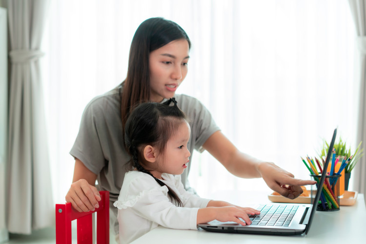 A parent and child engage in online learning on a computer.