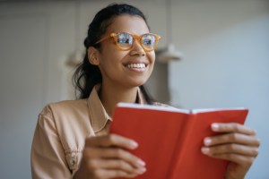 A smiling person reading a book.