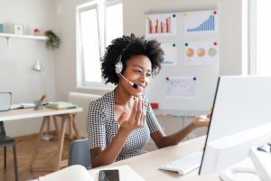 A person wearing a headset works from home on a computer.