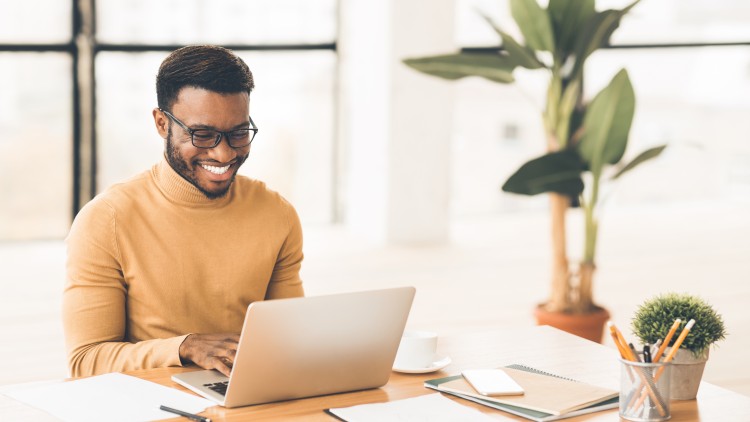 Certificate student smiling and working online from a laptop.