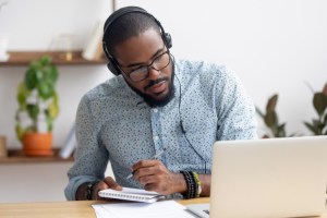 Person wearing headphones and studying at a desk with a computer.