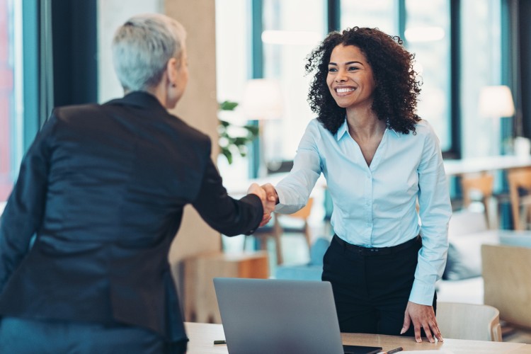 A smiling job applicant shakes hands with an interviewer.