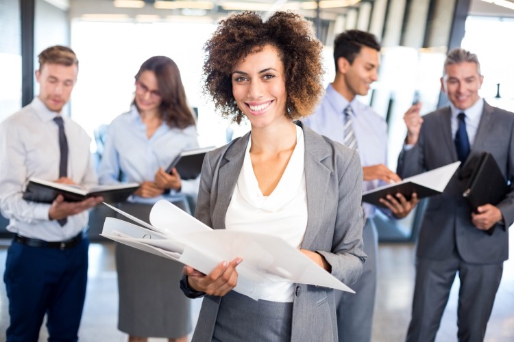 A smiling COO holds a binder of documents