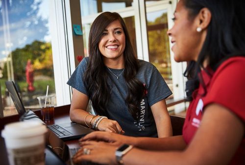 Student support specialist helping online student in cafe