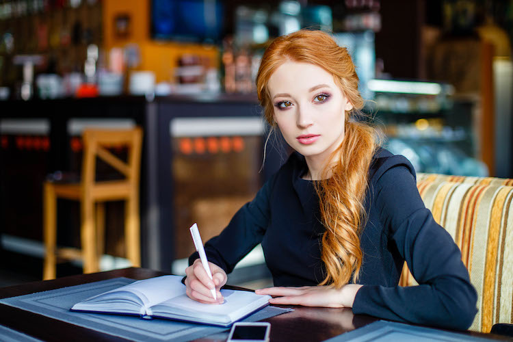 Author sits in a cafe and brainstorms a topic idea to write.