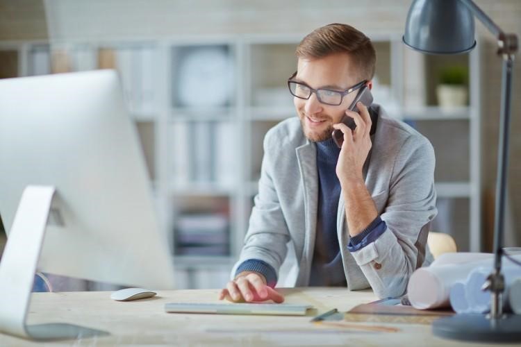 A social work case manager makes a phone call at his desk.