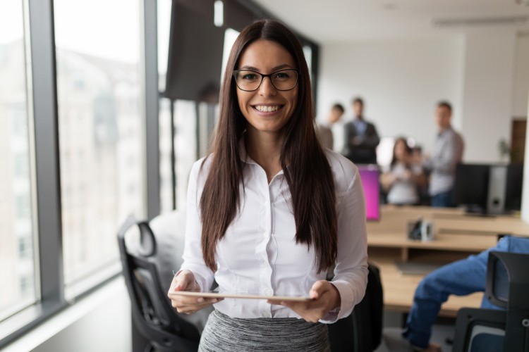 A smiling businessperson standing in a boardroom.