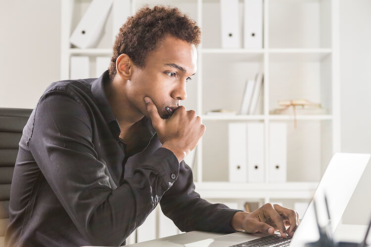 man looking at computer screen and thinking