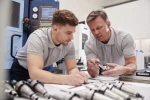 Engineer shows apprentice how to measure drawings.