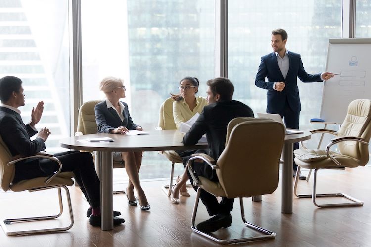 An executive leads a board meeting by conducting a presentation to board members