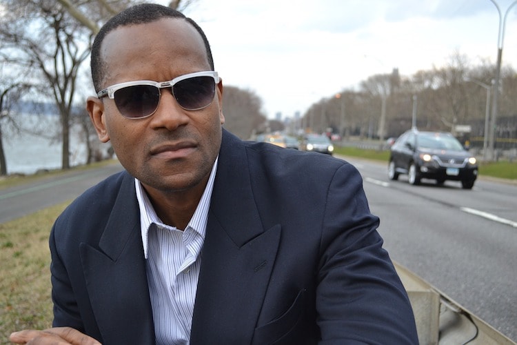 Man with sunglasses and suit beside a road 