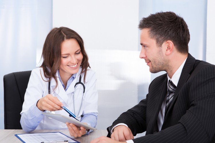 A doctor, pointing to a document, and a social worker sit at a conference table.