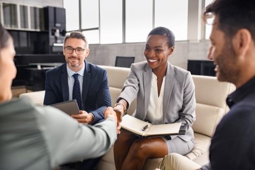 A smiling HR manager shakes hands with a new hire.