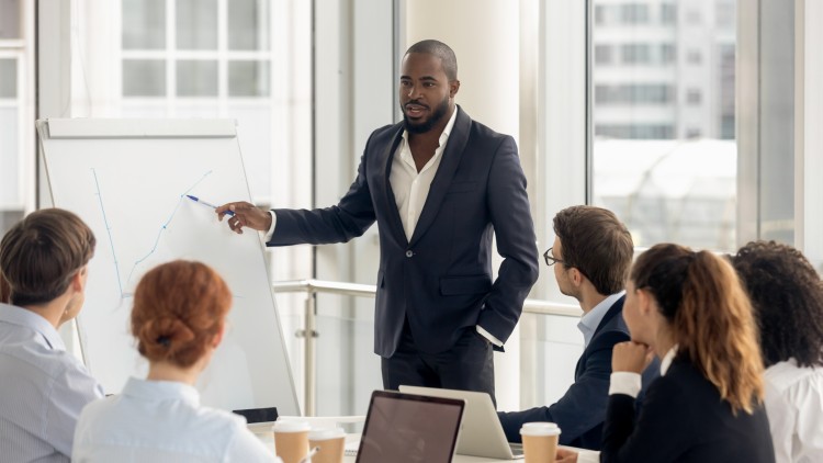 A CFO is giving a presentation to a finance team while standing at a flipchart.