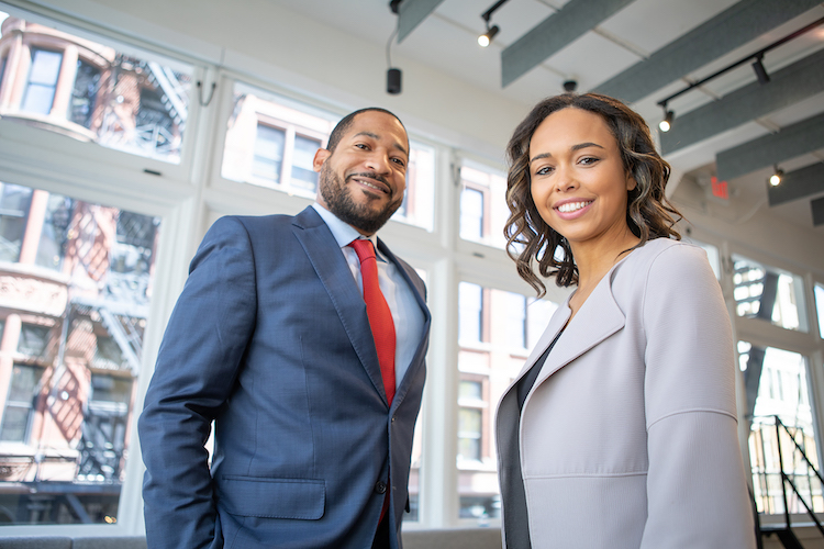 A man and woman wearing suits while smiling