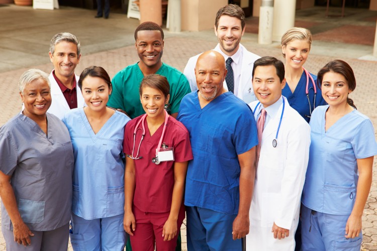 Smiling medical staff stand outside a hospital