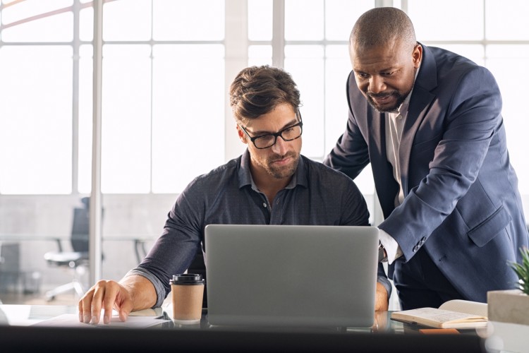 An operations manager points to an employee’s laptop screen.