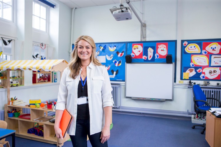 Preschool director standing in a classroom with a file folder in her hand.