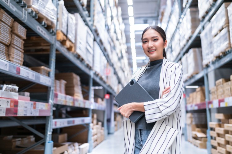 A product manager holding a tablet in a warehouse.