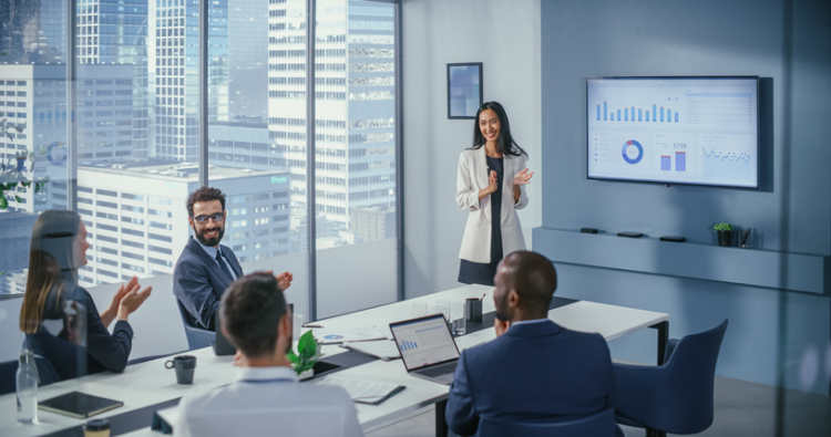 A VP of finance presenting a presentation with visuals to team members in a conference room. 