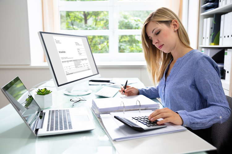 Young Businesswoman Calculating Bill With Computer And Laptop On Desk