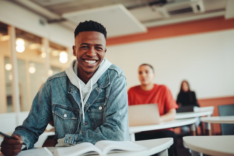 A smiling college student in a classroom.