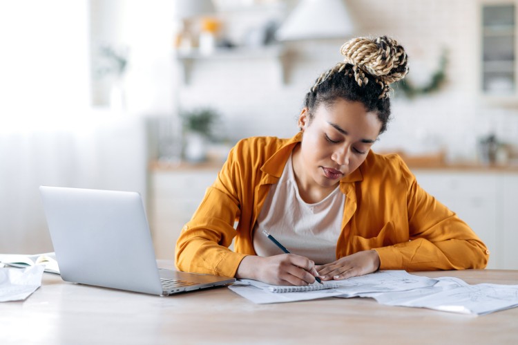 A student uses a laptop and written notes to study for an exam.